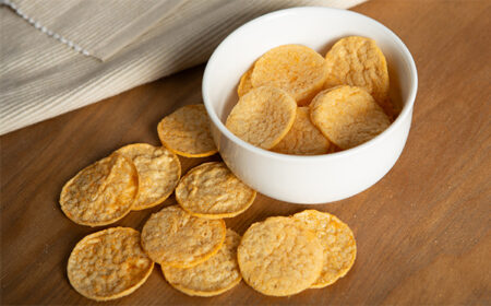 bbq popped chips in a white bowl and scattered on table